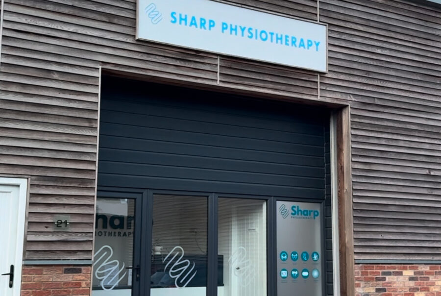 Front entrance of Sharp Physiotherapy Lincoln clinic with modern signage and glass doors at Cedar Parc.